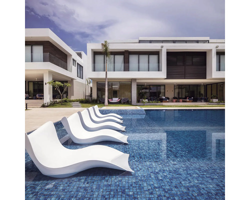 Zwembad met ligstoelen en moderne woonhuizen op de achtergrond