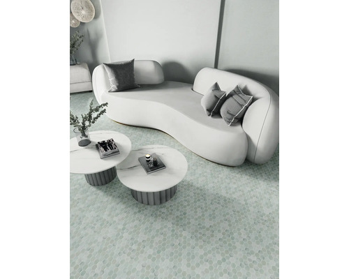 Lichte scène met een gebogen bank, kussens en ronde tafels op een gemusterde vloer