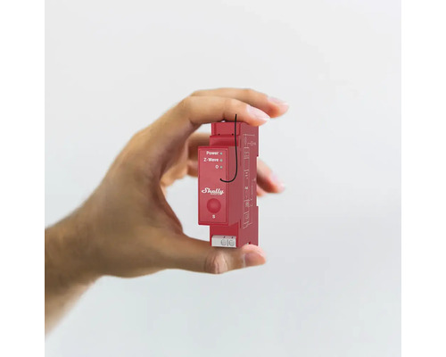 Een hand houdt een rood Shelly apparaat voor domotica vast