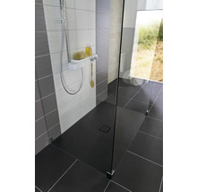 Gelijkvloerse douche met douchegoot, douchearmatuur en glazen wand in een modern ontworpen badkamer.