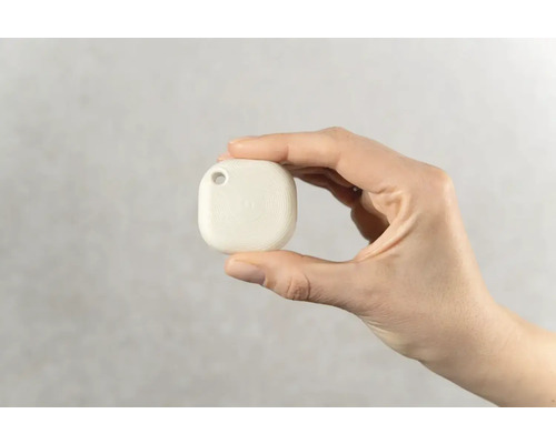 Hand houdt een witte volgapparaat-hanger met gat voor bevestiging vast