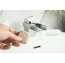 Een persoon houdt een aromasteen vast voor een kraan in de badkamer
