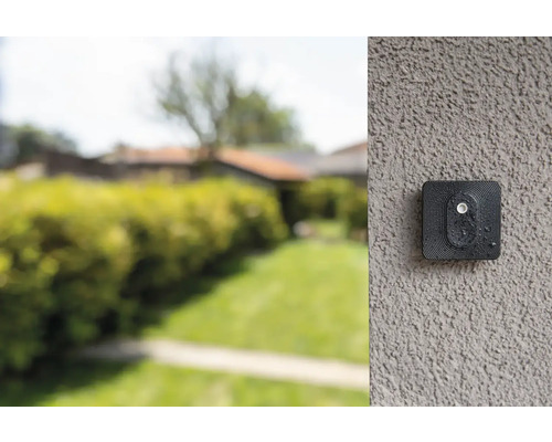Bewakingscamera aan een muur met tuin op de achtergrond