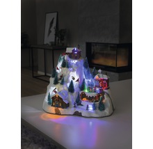 Decoratieve, verlichte winterdorp scène met huizen en figuren op een besneeuwde berg