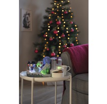 Decoratieve kerstscène met verlichte skihelling, kop, schaal en kerstboom op de achtergrond
