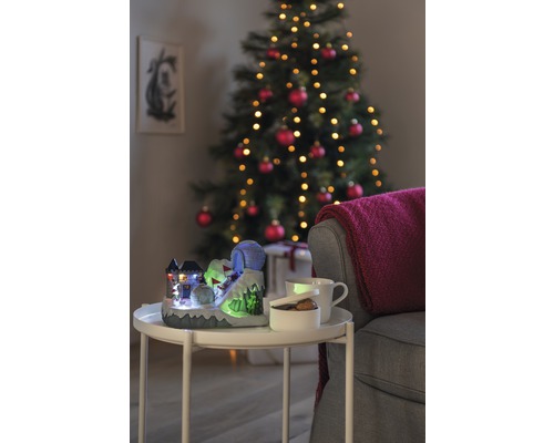 Decoratieve kerstscène met verlichte skihelling, kop, schaal en kerstboom op de achtergrond