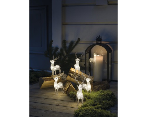 Decoratieve scène met verlichte rendierfiguren, houtblokken en een lantaarn