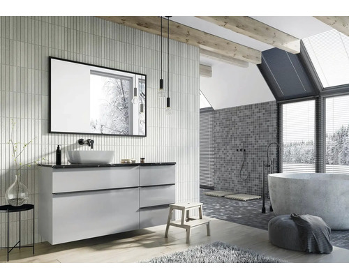 Lichte badkamer met wastafel, spiegel, bad en mozaïektegels op de muur.