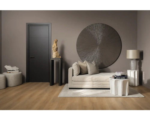 Inrichtingsvoorbeeld met deur, ligbed, decoratie en bijzettafels in een woonkamer.