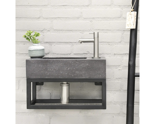 Wastafelmeubel met kraan, plant en handdoekenrek voor een bakstenen muur