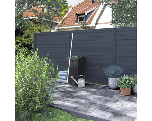 Tuinaanzicht met schuttingelementen, vuilnisbak en tuingereedschap