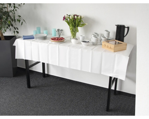 Tafel met wit tafelkleed, servies, drankjes, taart en bloemen