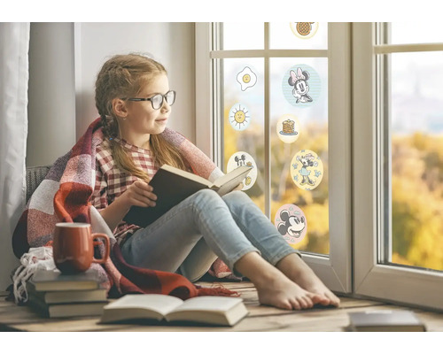 Meisje leest boek bij raam met Disney-stickers