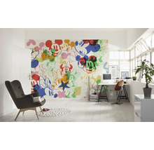 Lichte kamer met een wandbehang met Mickey Mouse motieven, een bureau en een fauteuil.