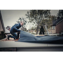 Ambachtsman legt dakbedekking op een plat dak