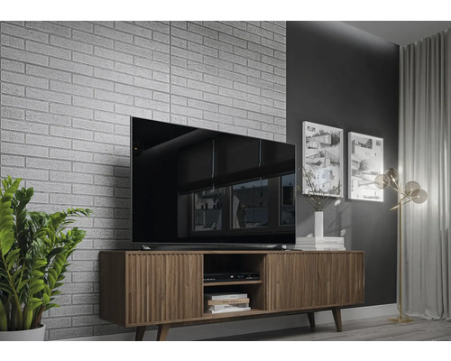 Woonkamer met televisie, tv-meubel en decoratieve bakstenen muur.