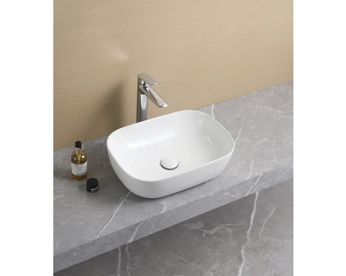 Opzetwastafel van keramiek op een werkblad met kraan