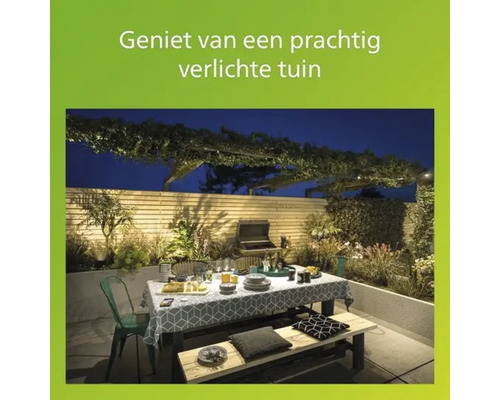 Verlichte tuin met eettafel en barbecue in de avond