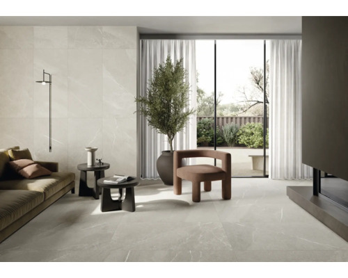 Woonkamer met tegelvloer en wandtegels in marmerlook, bank, fauteuils en kamerplant.