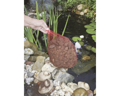 Persoon houdt een netzak met lavastenen boven een vijver