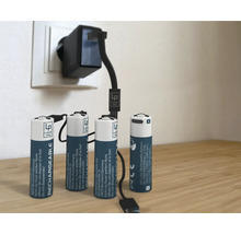 Vier oplaadbare batterijen met oplader in het stopcontact