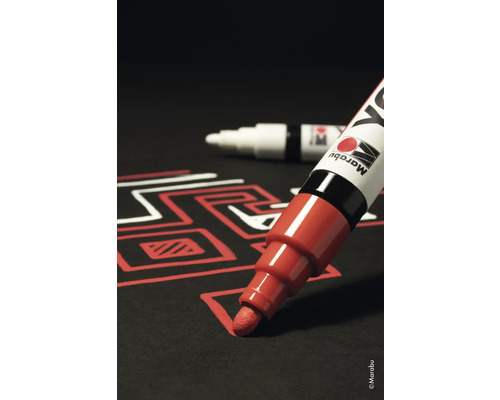 Een rode lakstift tekent een lijn op zwart papier. Een andere stift ligt op de achtergrond.