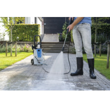 Persoon reinigt bestrating met een hogedrukreiniger buitenshuis.