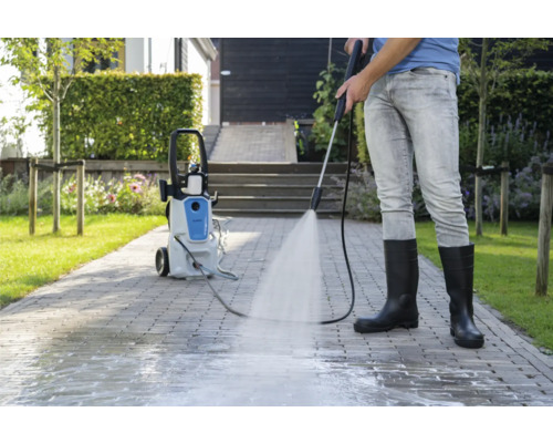 Persoon reinigt bestrating met een hogedrukreiniger buitenshuis.