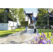 Man reinigt bestrating met een hogedrukreiniger voor een woonhuis.