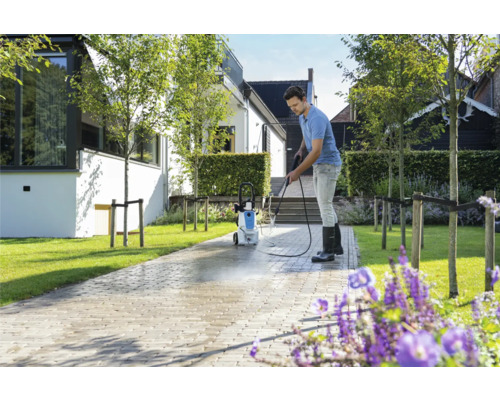 Man reinigt bestrating met een hogedrukreiniger voor een woonhuis.