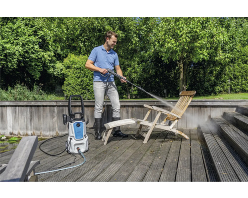 Man reinigt houten stoel met hogedrukreiniger buitenshuis.