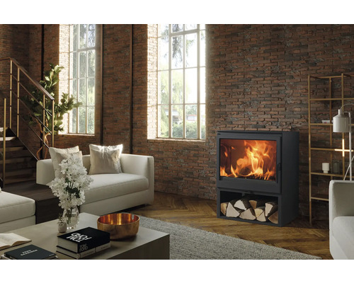 Woonkamer met houtkachel, houtblokken en bakstenen muur