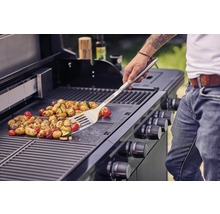 Groenten worden bereid op een barbecue met een barbecuespatel.