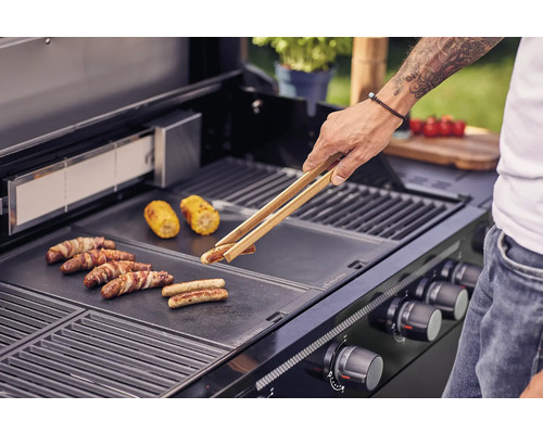 Man grilt worstjes en maiskolven op een barbecue