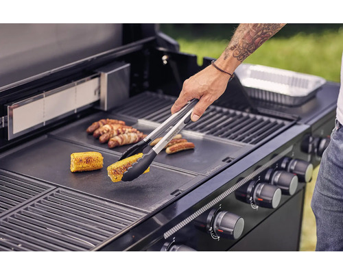 Persoon grilt maïs en worstjes op een barbecue.