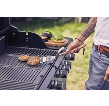 Persoon draait burgers op een grill met een spatel
