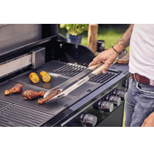 Man grilt kippenpoten en maiskolven met een grilltang op een barbecue