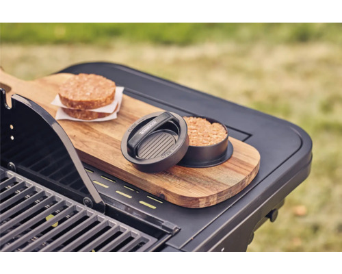 Burgerpers met twee vleesburgers op een grilltafel