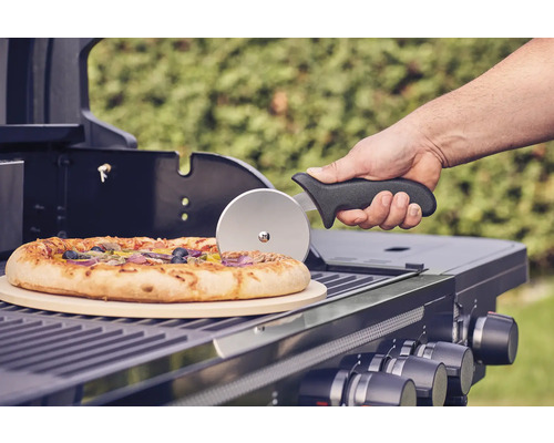 Pizza op een barbecue met pizzasteen en pizzasnijder.