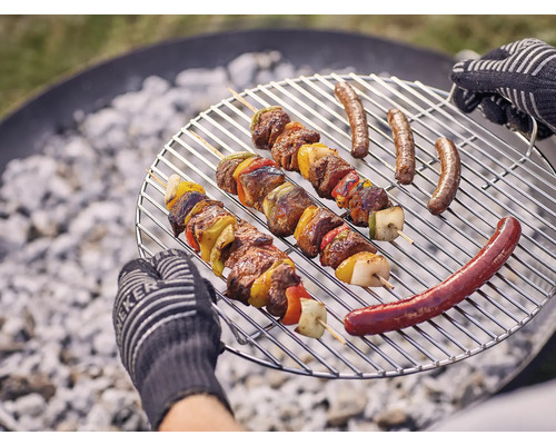 Grillrooster met vleesspiesjes en worstjes boven houtskool