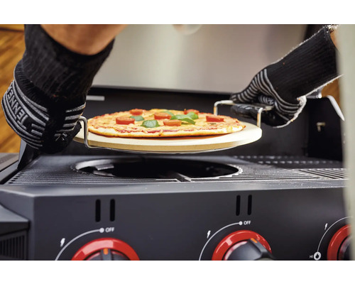 Pizza op een pizzasteen wordt in een gasbarbecue geschoven