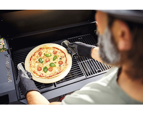 Een pizza op een pizzasteen wordt met een grill in een barbecue bereid.