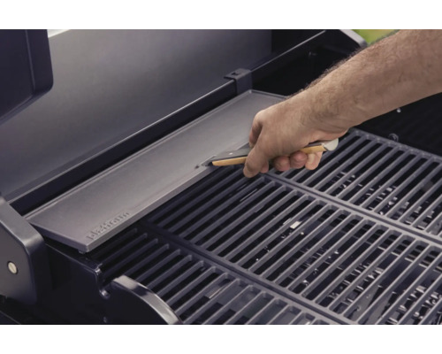 Een man legt een grillplaat op een grillrooster.