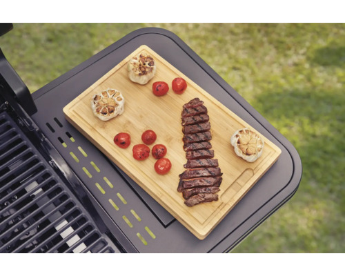 Barbecue met snijplank, knoflook, tomaten en gesneden steak