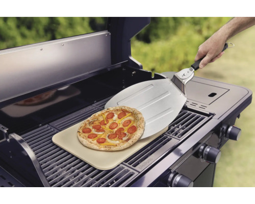 Pizza op een pizzasteen op een barbecue met een pizzaschep