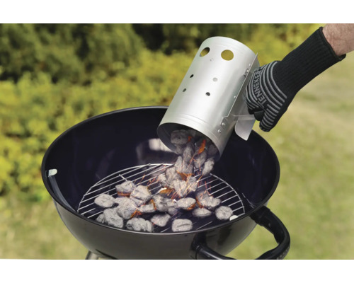 Persoon giet houtskool uit een schoorsteenstarter in een kogelbarbecue.