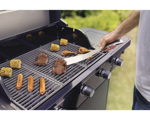Persoon grilt steaks, worstjes, mais en kip op een gasbarbecue.