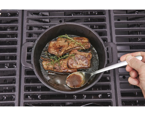 Twee steaks met rozemarijn bereid in een gietijzeren pan op een barbecue