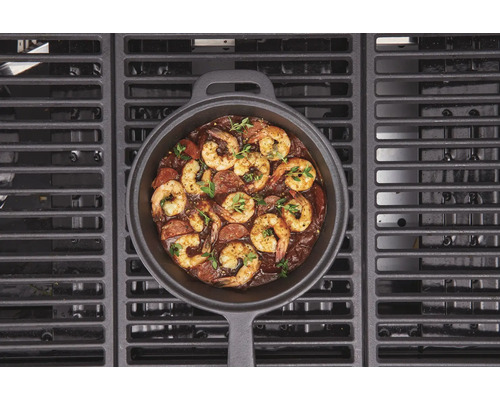 Gietijzeren pan met garnalen en worst op een barbecue