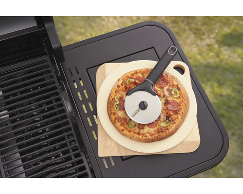 Pizza op houten plank met pizzasnijder naast een grill
